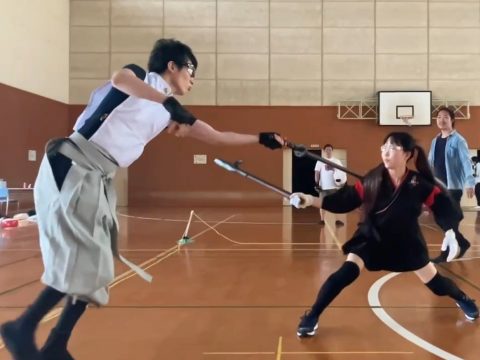 跳んでくのいちの攻撃をかわす剣士の写真